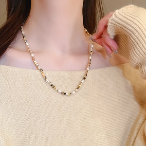 Detail of freshwater pearl and agate beaded necklace on model wearing beige knitwear