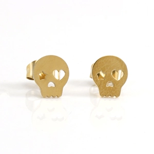 Détail des boucles d'oreilles tête de mort dorées en acier inoxydable poli sur fond blanc