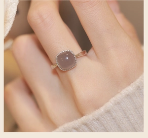 Detail of vintage square white jade stone ring with beaded metal border on the finger
