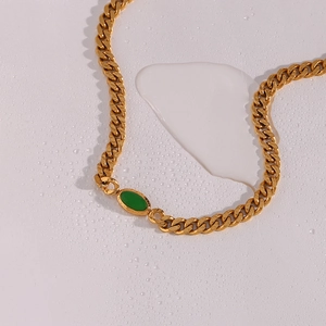 18K gold-plated chunky Cuban chain necklace with green oval gemstone on water-bead background