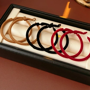 Three pairs of retro flocking hoop earrings in camel, black, and red inside a jewelry box