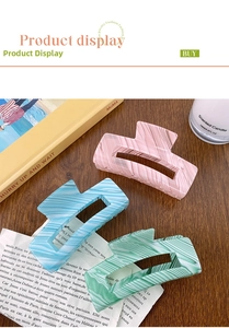 Close-up of three striped large hair claws in pink, blue and green on a wooden table