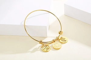 Detail view of a gold expandable Virgo zodiac bracelet with three charm pendants