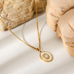 Macro detail of 18K gold stainless steel chain with white shell letter O pendant