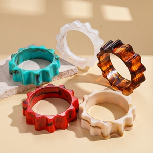 Set of five wavy resin acrylic bangles in marble and amber patterns on a stone base