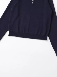 Close-up of navy knit sweater showing grey buttons and decorative white wave hem