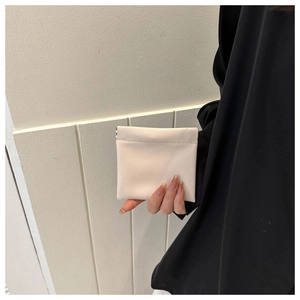 Close-up of a beige mini faux leather pouch with squeeze metal closure held in hand