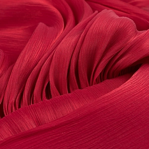 Macro shot of vibrant red pleated fabric with detailed vertical textures and silk finish