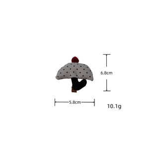 Detail view of a cute fabric mushroom hair clip with grey polka dots and red pom-pom