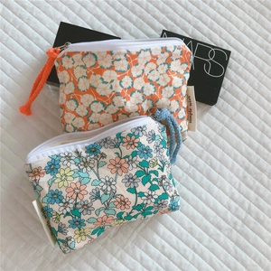 Detail view of two floral cotton coin purses with daisy patterns and zip closure
