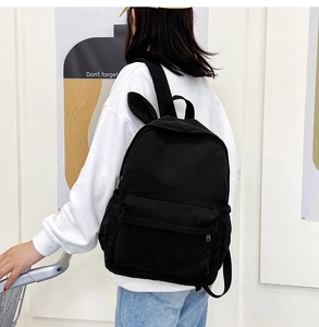 Detail of a large black rabbit ear backpack with durable canvas fabric shown on a model