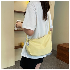 Detail of a pale yellow canvas hobo bag with a cute white dog charm on the zipper