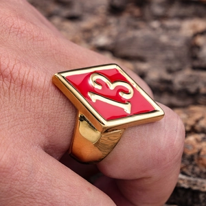 Close-up of a gold stainless steel biker ring featuring a red diamond face with number 13