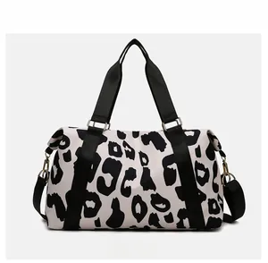Front view of cow print travel bag with black webbing handles and gold metal hardware