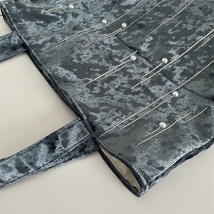 Detail of velvet tote bag featuring pearl embellishments and quilted texture