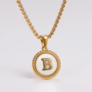 Detailed view of golden round shell pendant necklace featuring a 3D letter B and beaded edge
