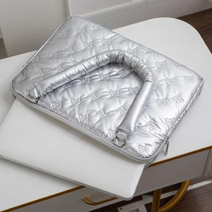 Macro detail of silver quilted laptop bag with bow pattern and padded handles