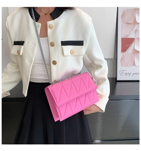 Close-up of bright pink quilted crossbody bag with silver chain and geometric pattern