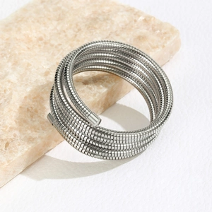 Minimalist silver multilayer stainless steel spiral coil bracelet on beige stone base