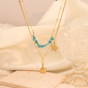 Detail of bohemian gold layered necklace with starfish, sea turtle, and turquoise beads