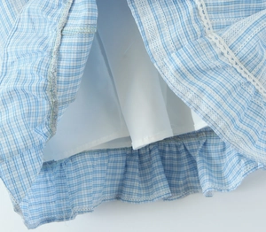 Detailed view of blue plaid dress hem featuring white lace trim and soft inner lining