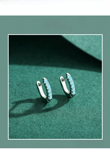 Macro shot of S925 sterling silver hoop earrings with seven turquoise stones on paper