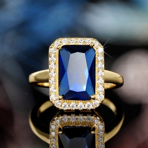 Vintage gold ring featuring a rectangular blue gemstone surrounded by crystals with reflection