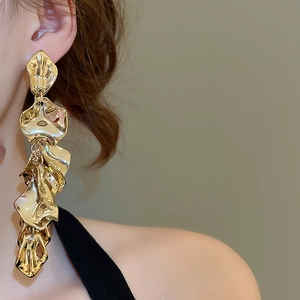 Close-up of elegant gold long fringe tassel earrings on model with high metallic luster