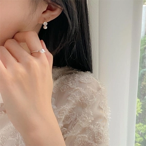 Close-up of elegant gold earrings with pearls and zircon on model in soft natural light