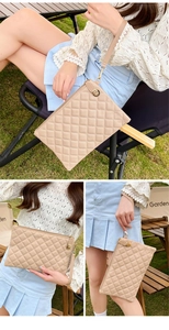 Detail of beige quilted leather clutch with metal chain hook and wrist strap in outdoor setting