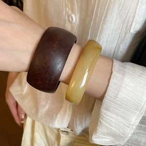 Detail view of stacked brown resin and honey amber-tone bangles on a woman's wrist