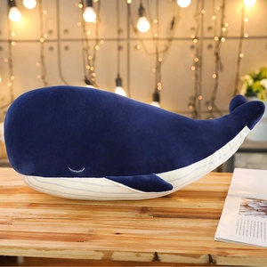 Detail of soft blue plush whale pillow with stripe belly on wooden table background
