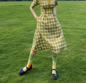 Dettaglio vestito a quadri giallo e bianco con calze medie e scarpe nere con plateau