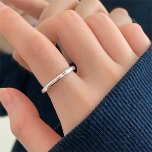Minimalist 925 sterling silver smiley face ring on a finger with blue knit sleeve