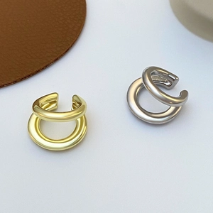 Detalle de pendientes de doble capa minimalistas en oro y plata con acabado pulido