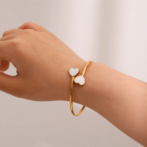 Detail of model wearing a gold 18k plated open heart bangle with white enamel inlay