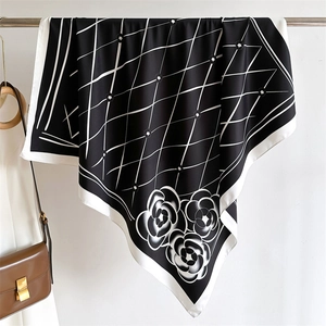 Detail of silk scarf with geometric grid and camellia flowers on a metal hanger