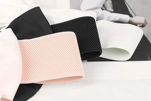 Detail of waffle-knit elastic waist belts in black, pink and white on a clean background