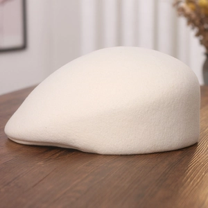 Detail of cream wool felt newsboy cap with smooth texture on a wooden table