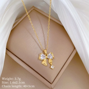 Detail of gold bow necklace with sparkling zircon pendant in a beige jewelry box