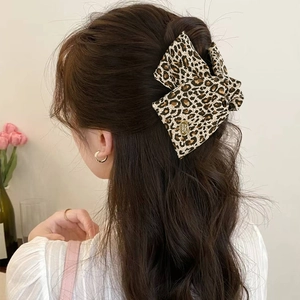 Détail d'une pince à cheveux vintage à motif léopard en tissu portée sur les cheveux