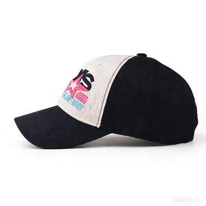 Detail of embroidered star and letters on a beige and black cotton baseball cap