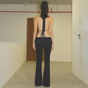 Vista posteriore del top allacciato al collo e pantaloni a zampa neri eleganti