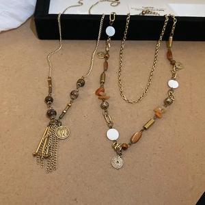 Dettaglio del ciondolo moneta vintage con nappe e collana di perline a strati