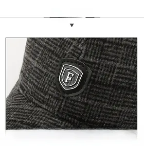 Close-up of thick grey knit texture and shield-shaped metal F logo on the winter baseball cap