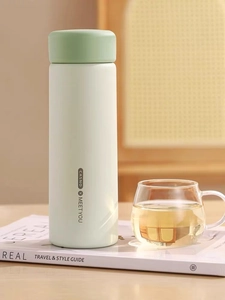 Close-up of matte mint green insulated bottle placed on a stylish lifestyle magazine