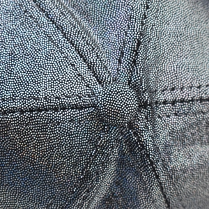 Close-up macro view of holographic glitter baseball cap top button and PU texture.