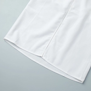 Close-up of the side slit detail on white woven cotton linen long dress hem