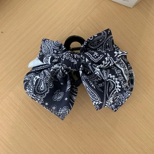 Pince à cheveux noeud en tissu bleu marine à motif paisley sur fond bois clair