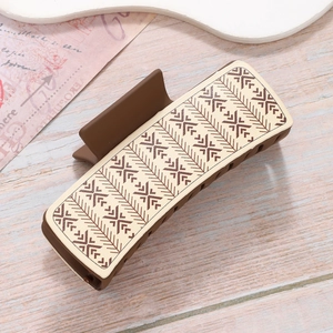 Brown matte rectangle hair claw clip with cream geometric pattern on wood surface